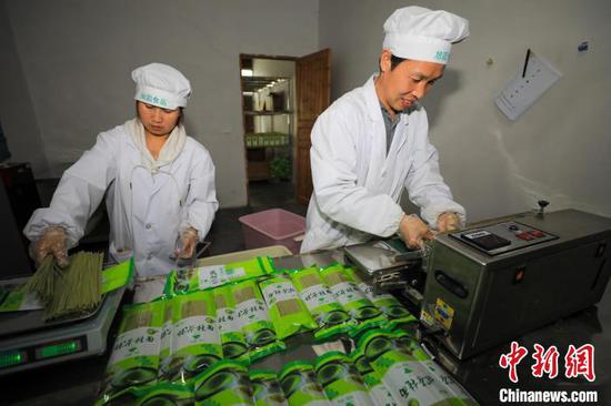 工人在贵州省江口县双江街道一家食品加工企业为抹茶面条装袋。　李鹤 摄
