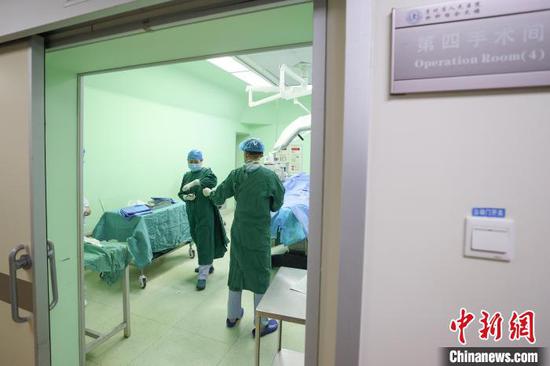 贵州省人民医院手术室内一位护士在同事协助下穿戴手术衣。　瞿宏伦 摄