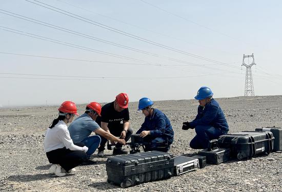 5月12日，国网吐鲁番供电公司输电巡检人员带电力客户体验高温巡线工作，展示无人机操作流程。张明先 摄