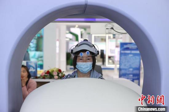 参观者在贵州省人民医院展区体验一款“人体电阻抗评测分析仪”。　瞿宏伦 摄