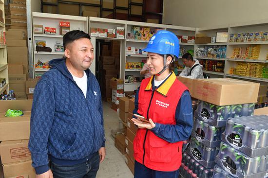 国网霍尔果斯市供电公司城区供电所员工在中哈霍尔果斯国际边境合作中心向哈萨克斯坦商人哈米了解电力供应情况。