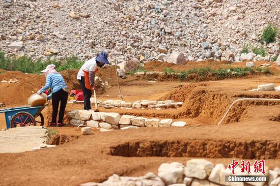 5月24日，工作人员在大松山墓群挖掘区域对地表进行刮面作业。