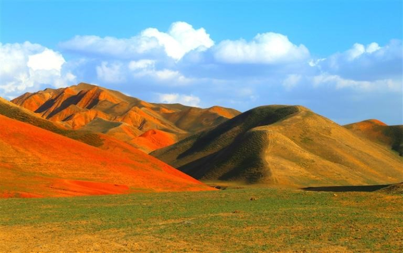 在新疆昌吉州阜康市南部山区水磨河河畔的小红沟，春日暖阳里的山地丘陵呈现出深浅不一、五彩斑斓的色带。
