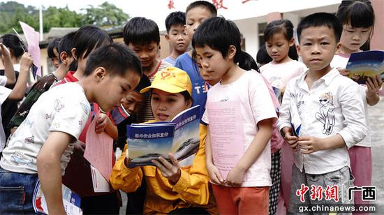 图为玉林工务段青年志愿者向小学生发放铁路安全宣传手册和爱路护路宣传单。谭育俊  摄