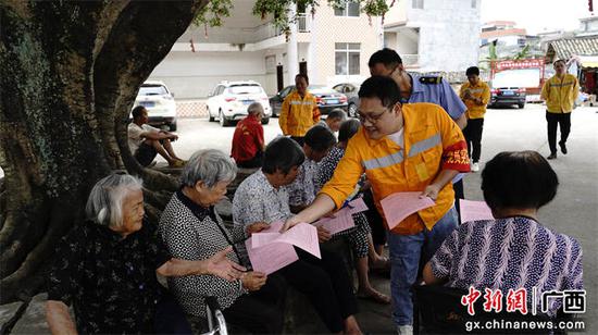图为玉林工务段青年志愿者深入沿线在给沿线村屯村民发放铁路安全宣传知识手册和宣传单。谭育俊  摄