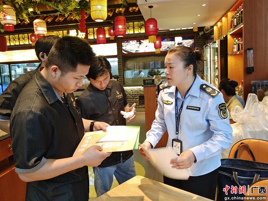 广西田林县市场监管局执法人员开展制止餐饮浪费宣传。黄碧静摄