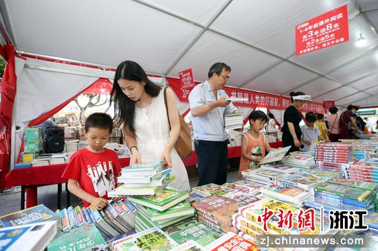 金华东阳，家长带孩子到“图书巡展”活动现场购买书籍。 
 胡扬辉（通讯员） 摄