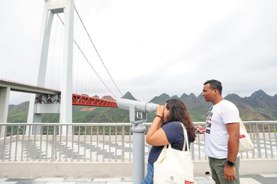 留学生通过望远镜观察坝陵河大桥结构。