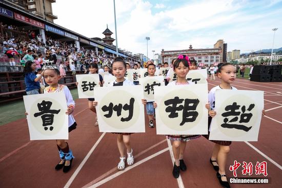 6月10日，啦啦队小队员手举“贵州村超”书法作品巡游。