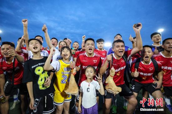6月10日晚，场坝村足球队队员拿着所获奖品——“猪腿”合影。