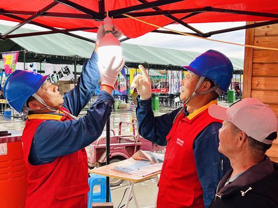 5月19日，国网博尔塔拉供电公司员工在阿热勒托海“中国旅游日”活动现场为商户解决电力问题，保障客户生产生活用电无忧。朱丽 摄