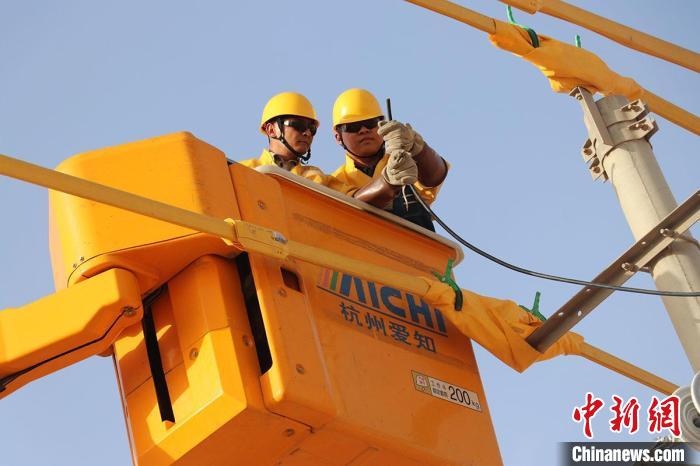 国网吐鲁番供电公司带电作业职工在高昌区火焰山镇带电接入100千伏安机井专用变压器。　汪泽超　摄