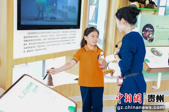展览馆室内展区，前来参观的小朋友向讲解员询问观山湖区生物多样性的知识