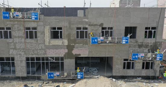 图为工人们正在对沿街单体建筑物进行墙面粉刷 董帅龙摄