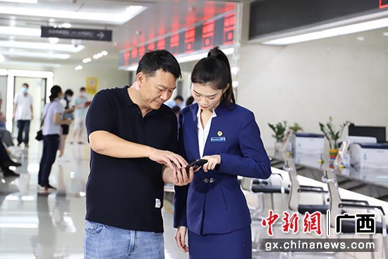 工作人员指导南宁市民使用“邕e登”手机APP。