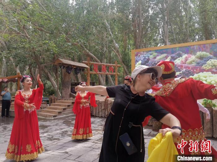 产业融合助推吐鲁番葡萄产业提质升级。图为游客在葡萄沟景区载歌载舞。　胡嘉琛　摄