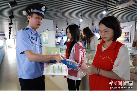 民警向学生们发放禁毒宣传资料。蒙正欢 摄