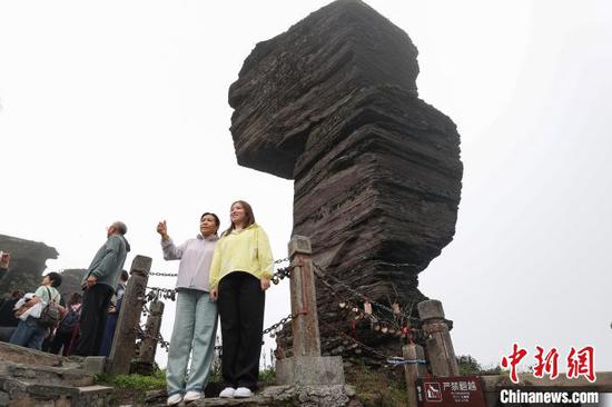 图为游客在世界自然遗产地梵净山蘑菇石下打卡拍照。　瞿宏伦 摄