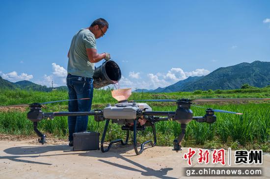 图为农户在贵州省松桃县普觉镇猫猫屯坝区给无人机装农药。唐哲 摄