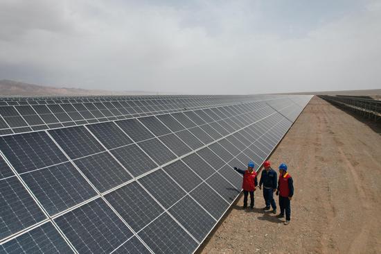 6月30日，国网阿克苏供电公司工作人员努尔·艾合买提和牛宏伟在新疆华电库车（牙哈）550兆瓦光伏发电项目光伏基地了解光伏光伏发电上网情况。马海骄 摄