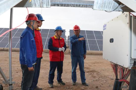 6月30日，国网阿克苏供电公司工作人员努尔·艾合买提和牛宏伟在新疆华电库车（牙哈）550兆瓦光伏发电项目光伏基地了解逆变器工作情况。常帅 摄