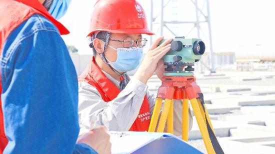 2021年8月30日，国网新疆建设分公司员工在乌昌750千伏变电站对GIS设备进行水平标高抽查。（伍建波 摄）
