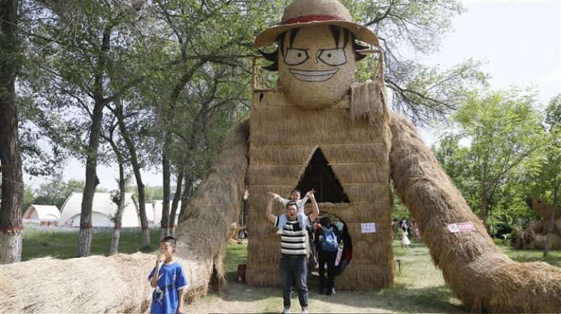 　　游客在巨型稻草人王國游玩拍照。

