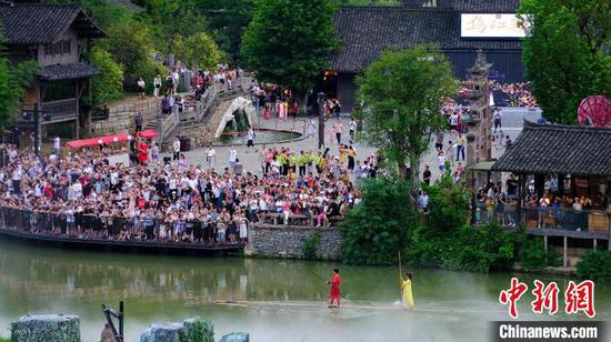 游客在贵州省遵义市播州区乌江寨景区观看独竹漂表演。　伍卫东 摄