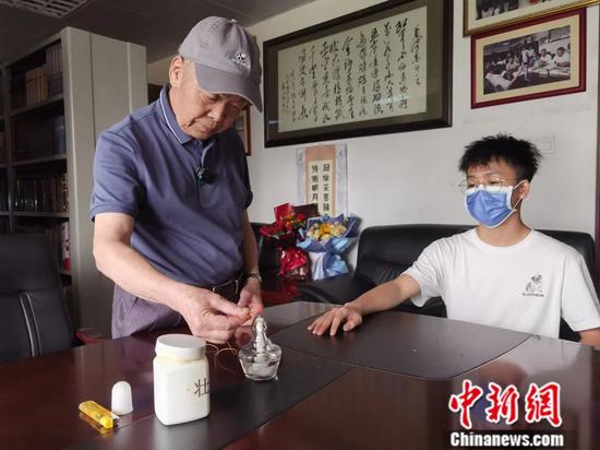 黄汉儒(左)准备为患者进行药线点灸治疗。杨陈 摄