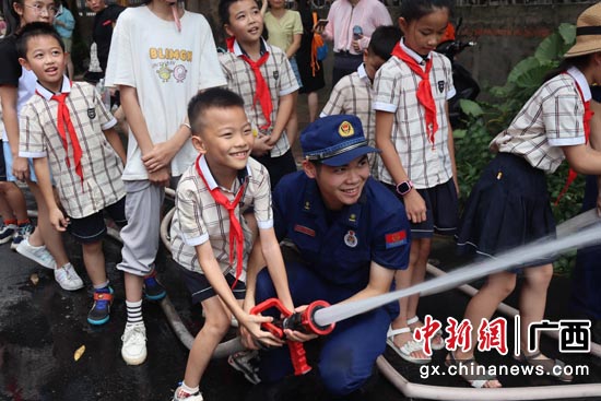 孩子们在消防员的帮助下，体验消防水枪。南宁高新区消防救援大队 供图
