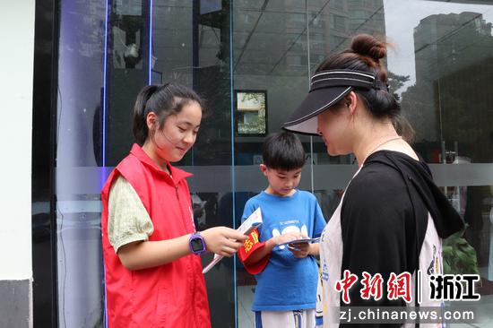 孩子们身穿志愿者红马甲，为前来投放生活垃圾的居民们讲解具体分类方法    吴明宪 摄