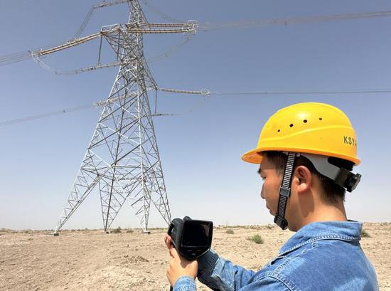 7月18日，室外温度43℃，新疆送变电公司员工在750千伏车楚一线480号铁塔进行红外测温。（刘洋 摄）