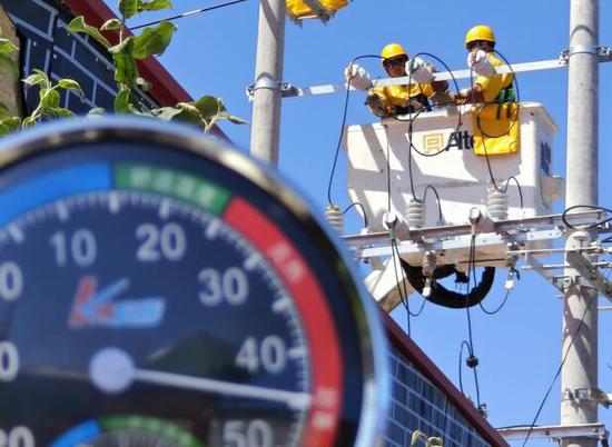 7月14日，国网伊犁伊河供电公司带电作业人员顶着44℃高温，开展带电接引流线工作。（汤雪霖 摄）
