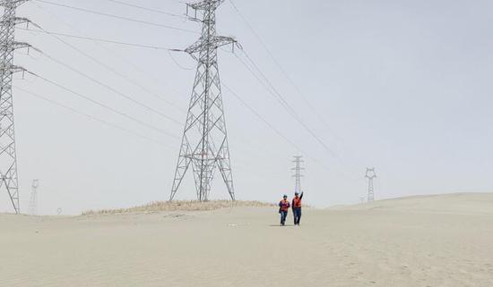 7月19日，国网和田供电公司员工冒着38°C的高温天气在沙漠中巡视线路，确保高温天气下电网安全可靠运行。（马明宇 摄）