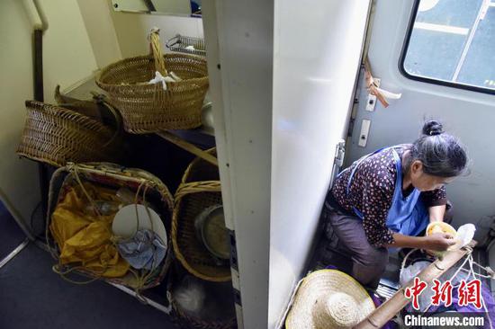 在5640次列车洗脸间处堆放着村民卖完菜的空竹篮，一旁的范余芝正在吃着泡面。　沈向全 摄