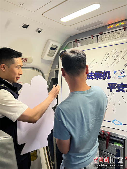 南航广西分公司安全员引导旅客在”依法乘机 平安出行“签字板上签名。张广大 摄