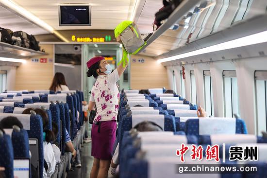 7月26日，贵阳北开往成都东的G5392次列车上，列车长在为旅客放包。 瞿宏伦 摄