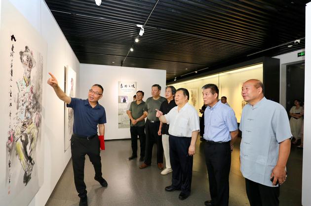 任惠中（左一）在画展现场介绍作品。刘俊苍