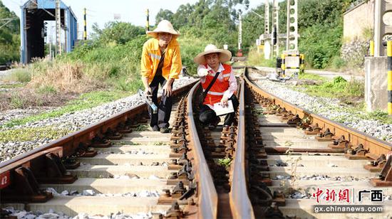 图为玉林工务段职工在烈日下目测道岔轨道框架和高低、水平参数变化情况。李慕传  摄