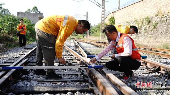 图为玉林工务段职工利用道尺检测道岔岔心轨距、水平参数变化情况。李慕传  摄