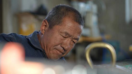 丁学生会根据之前测量好的马背宽度、厚度与马的高度,比照尺寸,一点点通过反复敲打调整马鞍骨架的形状 李蓉摄 丁学生会根据之前测量好的马背宽度、厚度与马的高度,比照尺寸,一点点通过反复敲打调整马鞍骨架的形状 李蓉摄