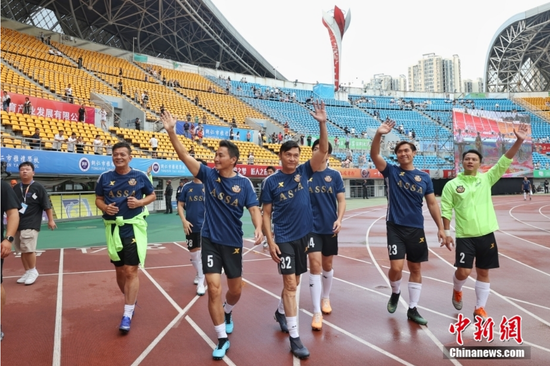 图为香港明星足球队队员热身时向观众挥手致意。
