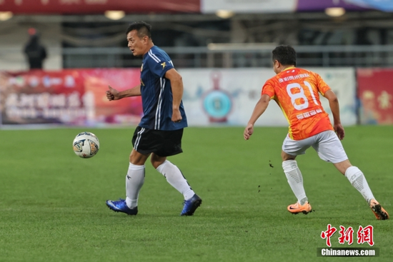 图为香港明星足球队队员黄日华（蓝衣）在比赛中带球。