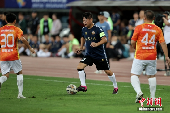 图为香港明星足球队队员陈百祥（蓝衣）带球突破。