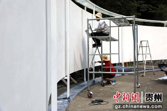 在大展第一篇章《壮阔山河间的力与美》施工现场，工人正在为建筑刷漆。王婵娟 摄