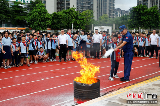 消防指战员指导学生进行 “油桶灭火”实操演练。潘志安 摄
