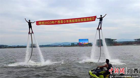 水上运动表演者挥动手中横幅标语预祝活动取得圆满成功。韦明 摄