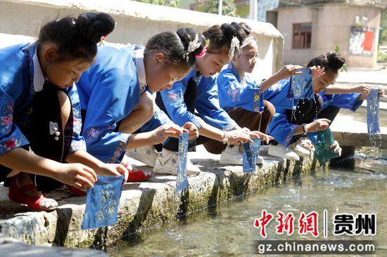 2023年8月30日在贵州施秉县双井镇苗族独木龙舟展示馆外学生们对染布进行漂洗。