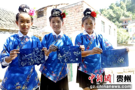 2023年8月30日在贵州施秉县双井镇苗族独木龙舟展示馆外学生们展示自己完成的蜡染“作业”。