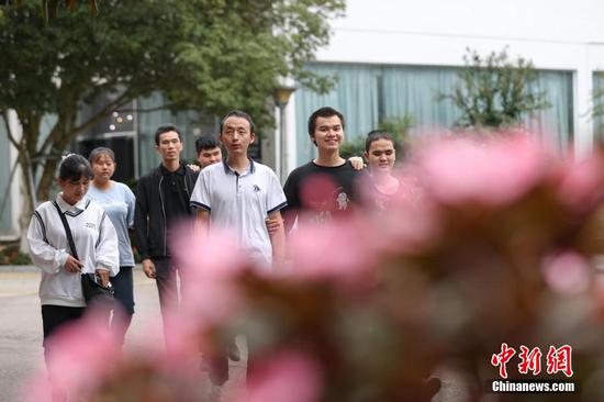 9月7日，贵州省惠水县，罗强（中）和学生们走在校园内。